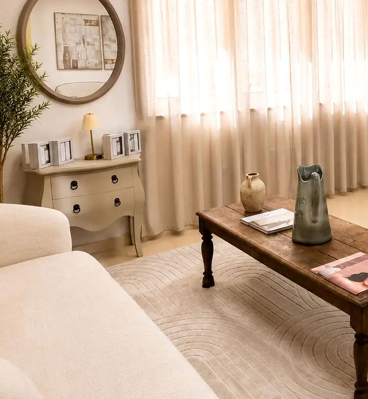 Recepción de la Clínica Ibiza Posidonia, con espejo redondo, cómoda y cortinas de lino