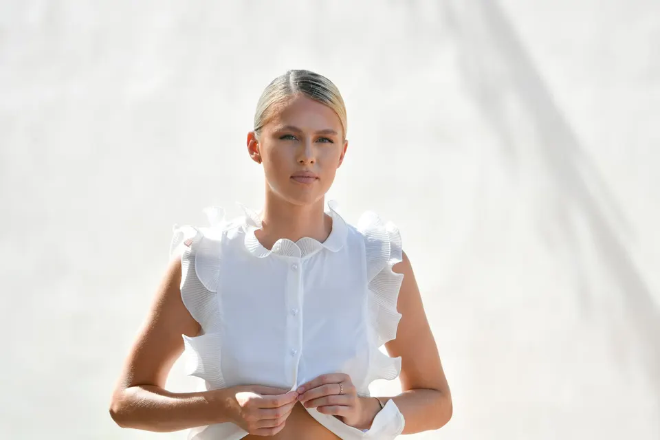 Mujer vestida de blanco ante una pared luminosa