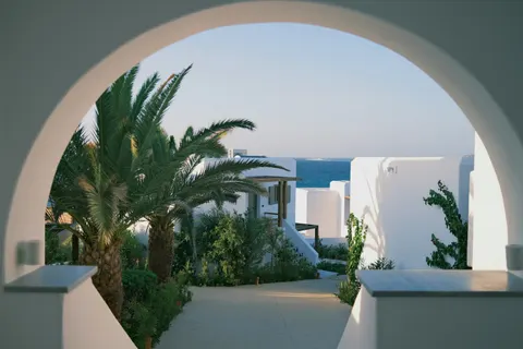 Arco blanco mediterráneo con palmeras y mar al fondo