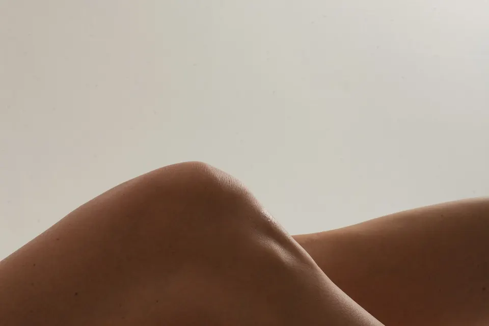 Piernas flexionadas con luz suave sobre fondo neutro
