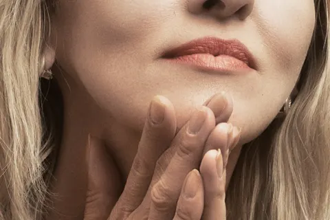 Mujer madura con las manos junto al mentón y el cuello