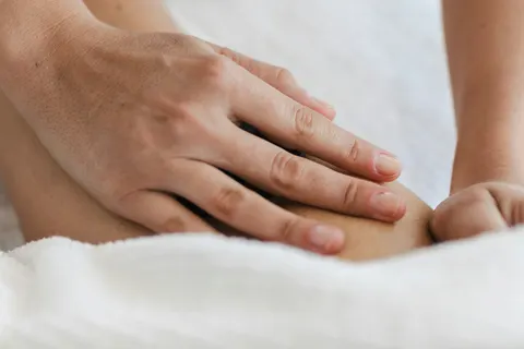 Manos tratando una pierna sobre una toalla blanca